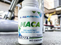 Bottle of AllNutrition Maca supplement in a gym setting