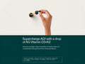 A hand holding a dropper above a white wall, with a dark teal banner at the bottom containing text that reads 'Supercharge AG1 with a drop of AG Vitamin D3+K2' and additional supplement information.