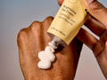 Hand applying brightening day cream to another hand