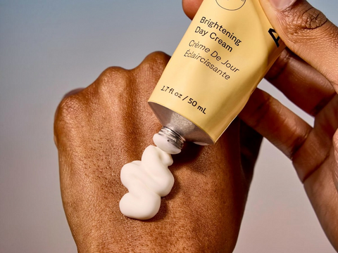 Hand applying brightening day cream to another hand