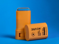 Two orange A Cure Invisible Sunscreen Stick containers on a blue background