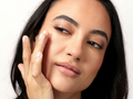 Woman touching her face with a neutral background