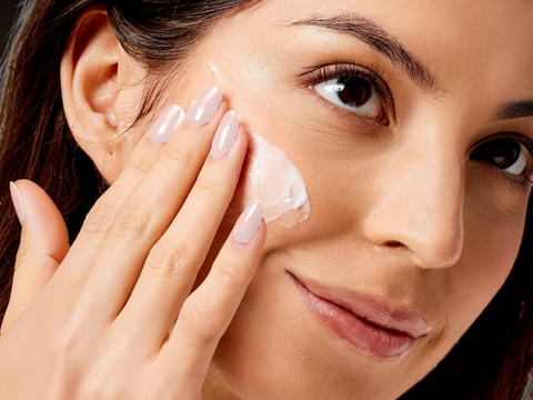 Woman applying cream to her face