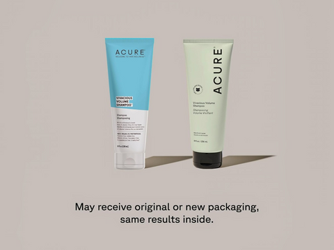 Two Acure shampoo bottles, one blue and one green, on a beige background.