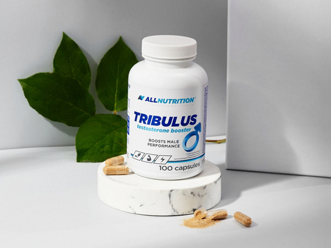 Tribulus supplement bottle with capsules on a white surface with green leaves in the background