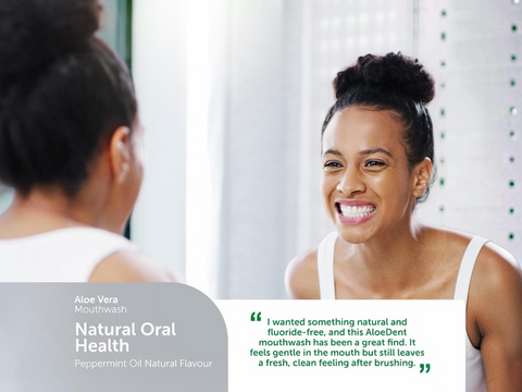 Woman smiling in front of a mirror with AloeDent mouthwash advertisement.
