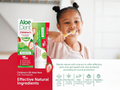 Aloe Dent children's toothpaste packaging with a child brushing teeth in the background