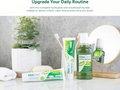 AloeDent toothpaste, mouthwash, and other dental care products on a bathroom counter with a plant and mirror in the background.
