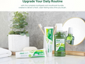 AloeDent toothpaste, mouthwash, and toothbrush on a bathroom counter with a plant and mirror in the background.