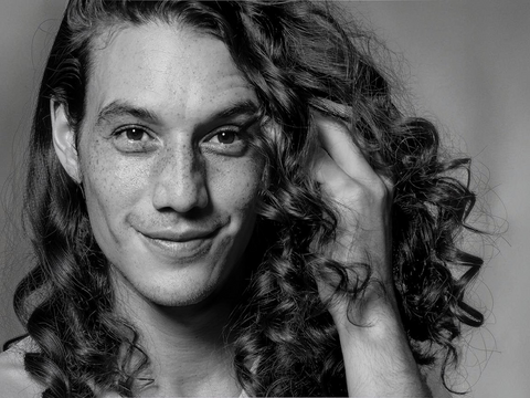 Black and white portrait of a person with long hair, smiling.