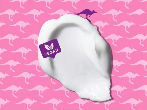 White cream on a white hand with a 'Vegan' label against a pink background with kangaroo patterns