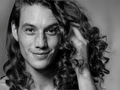 Black and white portrait of a person with long hair, smiling.