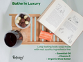 Bathe In Luxury soap bar with a book, bowl of fruit, and glass on a wooden tray.