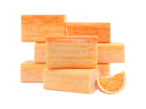 Orange-colored soap bars with 'Vitamin C' and 'Australian Botanical Soap' text, alongside a slice of orange on a white background.