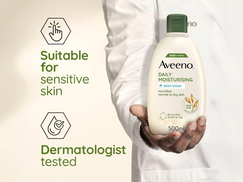 Aveeno body wash bottle held by a person with product details on a beige background