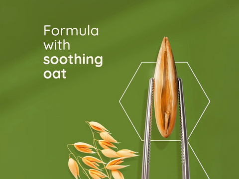 Oat kernel held by tweezers with text 'Formula with soothing oat' on a green background