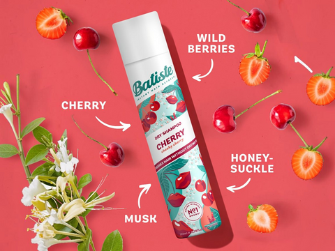 Batiste dry shampoo bottle with cherry flavor on a red background with cherry and strawberry elements.