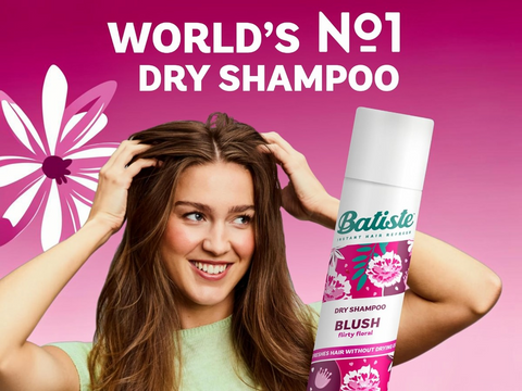 Woman holding Batiste dry shampoo with pink background and text claiming it's 'World's No.1'.
