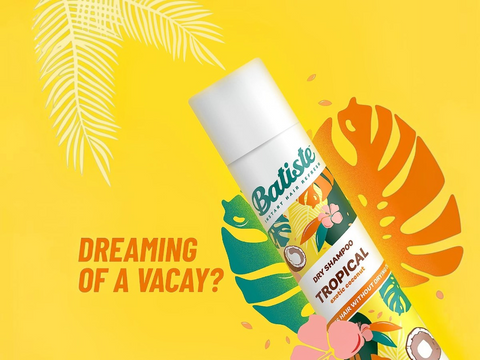Batiste Tropical dry shampoo bottle on a yellow background with decorative elements