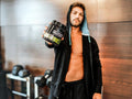 Man holding a supplement container in a gym setting