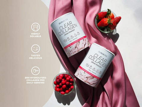 Two containers of 'Clear Collagen' drink powder with strawberries on a pink fabric background.