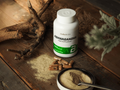 Biotech USA Ashwagandha supplement bottle on a wooden surface with powder and capsules.