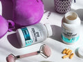 Coenzyme Q10 supplement bottles with pink roller and capsules on a white surface