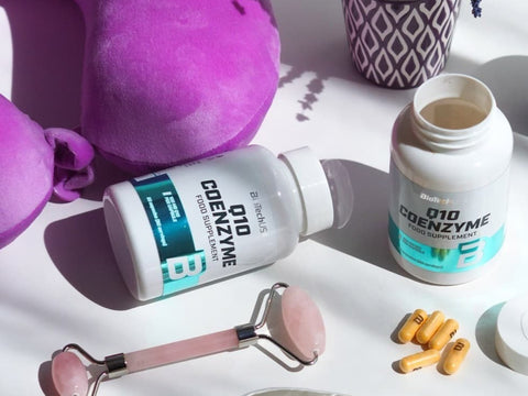 Coenzyme Q10 supplement bottles with pink roller and capsules on a white surface