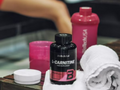 L-Carnitine supplement bottle with pink shaker and towel on a table