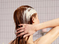 Coco & Eve Hydrating Conditioner with Coconut & Argan Oil. Rich conditioner being applied to long, wet hair.