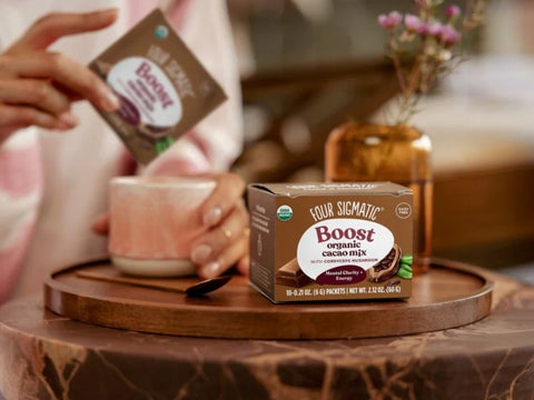 How to Use: Four Sigmatic Cacao Mix packet being stirred into a mug of hot water.