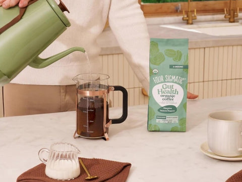 How to Use: Four Sigmatic ground coffee being scooped next to a coffee maker.