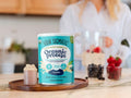 Four Sigmatic Organic Protein canister on a wooden board with a blurred kitchen background