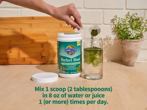 Garden of Life Perfect Food Super Greens Formula Powder scoop with green superfood powder next to tub