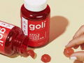 Red gummy bottle labeled 'goli' with gummies on a beige background