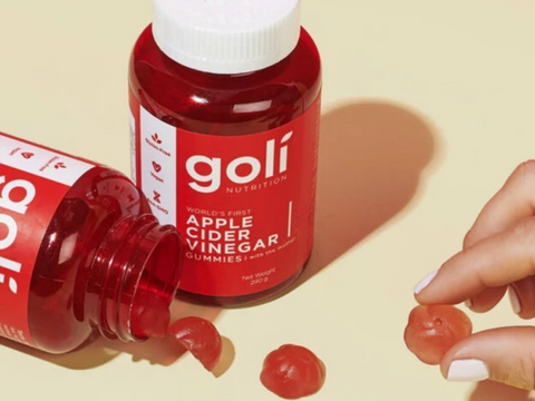 Red gummy bottle labeled 'goli' with gummies on a beige background