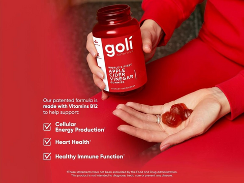 Person holding a red Goli supplement bottle with gummy bears on a red background
