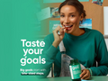 Woman holding a Goli probiotic bottle with text 'Taste your goals' on a green background