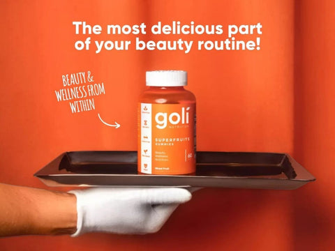 Goli supplement bottle on a tray with text about beauty routine against an orange background