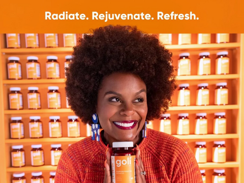 Woman holding a Goli supplement bottle with an orange background and product display.