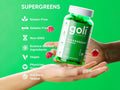 Goli SuperGreens gummy bottle held in a hand with green background and feature list.