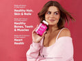 Woman holding a multivitamin bottle with product features on a pink background