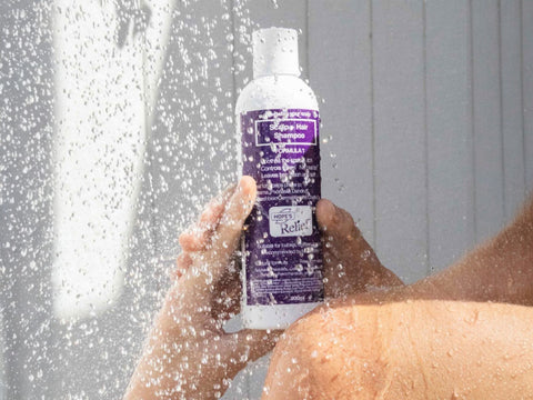 Person holding a bottle of shampoo under running water