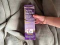 Hand holding a box of Hopes Relief shampoo for dry, itchy, flaky scalp on a gray fabric background.