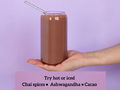Hand holding a glass of chocolate drink with a straw on a purple background, featuring text about drink options.