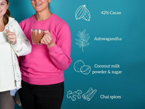 Two people holding a glass of chocolate drink with health ingredient illustrations on a blue background