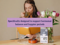 Woman drinking tea with flowers and a book on a table, text about hormonal balance.