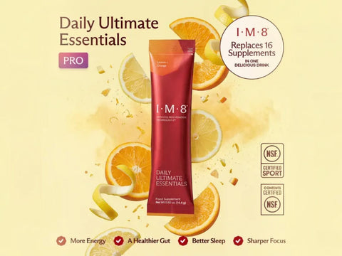 A red and orange I-M-8 Daily Ultimate Essentials PRO supplement tube centered on a pale yellow background with orange slices, lemon wedges, and citrus splashes. Text includes 'Daily Ultimate Essentials,' 'PRO,' 'I-M-8,' 'Replaces 16 Supplements in One Delicious Drink,' NSF Certified Sport and Common Certified logos, and benefit bullets at the bottom.