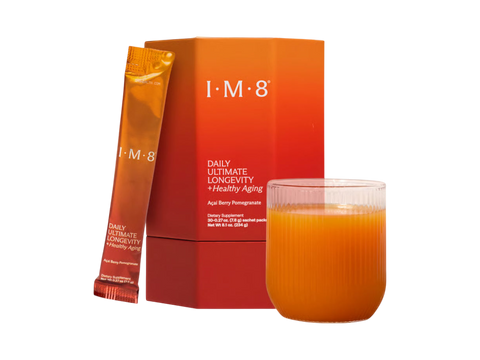 I-M-8 Daily Ultimate Longevity + Healthy Aging supplement shown with an orange and red box, a single orange sachet, and a glass of orange liquid on a white background.