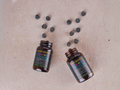 Two bottles of 'Body Biotics Gummies' by KIKI Health on a textured surface with scattered gummies.